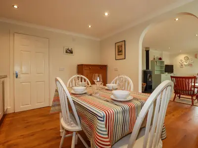 a dining room with a table and white chairs at 6 Trelawney Court in Wadebridge