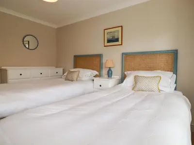 two beds in a bedroom with white sheets at 6 Trelawney Court in Wadebridge