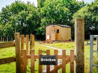 a wooden barn in a field next to a fence at Bracken in Bude