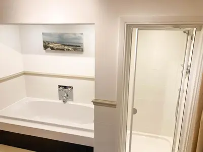 a bathroom with a bath tub and a sink at Birdsong in Carbis Bay