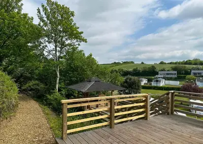 a wooden fence with an umbrella on a wooden deck at Calloose Holiday Park in Hayle