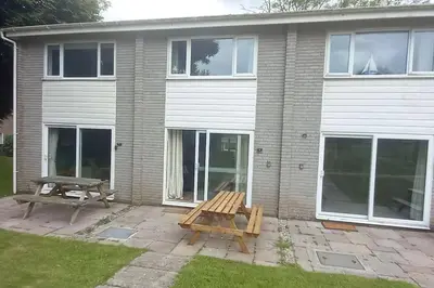 a picnic table and a bench in front of a house at Sunny holiday house in Newquay
