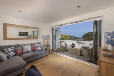 a living room with a couch and a large sliding glass door at 5 Sandy Lane Apartments, Carbis Bay in Carbis Bay