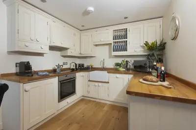 a kitchen with white cabinets and a wooden counter top at 5 Sandy Lane Apartments, Carbis Bay in Carbis Bay