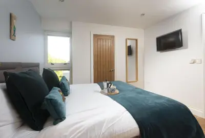 a bedroom with a large white bed with blue pillows at 5 Sandy Lane Apartments, Carbis Bay in Carbis Bay