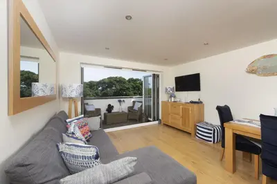 a living room with a couch and a desk at 5 Sandy Lane Apartments, Carbis Bay in Carbis Bay