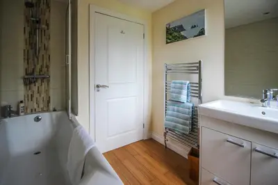 a bathroom with a white tub and a sink at Gardenia Cottage Cornwall in Wadebridge