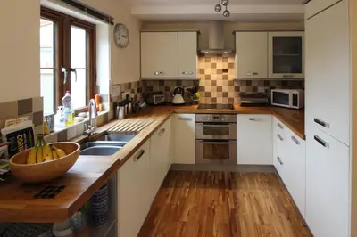 a kitchen with white cabinets and a wooden counter top at Gardenia Cottage Cornwall in Wadebridge