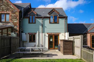 a house with a picnic table in front of it at Gardenia Cottage Cornwall in Wadebridge