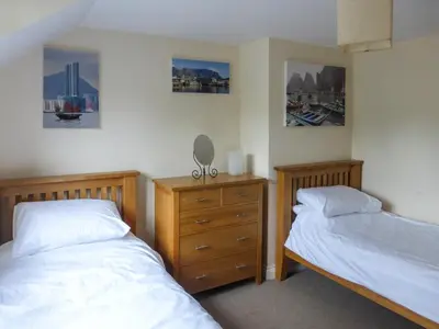 a bedroom with two beds and a dresser at Gardenia Cottage Cornwall in Wadebridge
