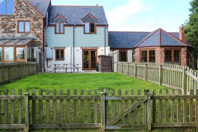 a wooden fence in front of a house at Gardenia Cottage Cornwall in Wadebridge