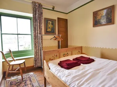 a bedroom with a bed and a chair and a window at 3 Bed in Polruan oc-pc032 in Fowey