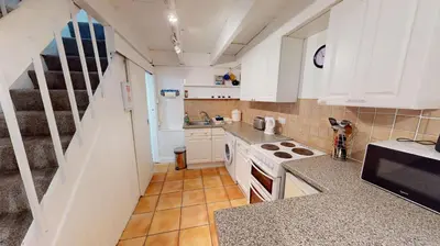 a small kitchen with white cabinets and a stove at St Ives Gazelle Cottage 2 Bedrooms in St Ives