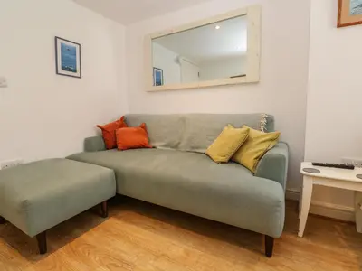 a living room with a couch and a mirror at Cormorant Cottage in St Ives