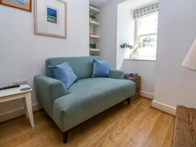 a green couch in a living room with a window at Cormorant Cottage in St Ives