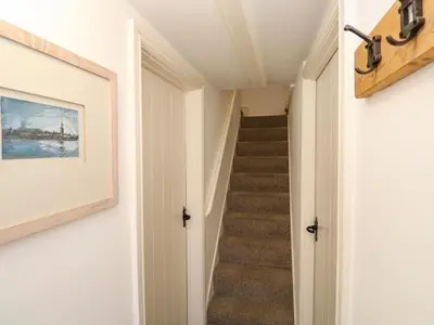 a hallway with stairs with a painting on the wall at Cormorant Cottage in St Ives