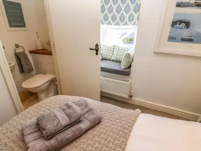 a bedroom with a bed and a window with a toilet at Cormorant Cottage in St Ives