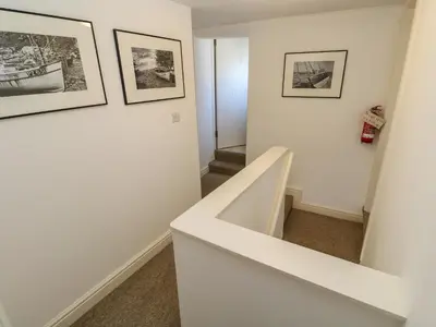 a staircase in a white room with pictures on the wall at Cormorant Cottage in St Ives