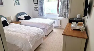 a bedroom with two beds and a table and a window at Wadebridge, 14 St Matthews Hill in Wadebridge