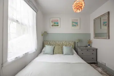 a bedroom with a bed and a window and a mirror at St Ives apartment less than 5 minutes walk to beach parking available in St Ives