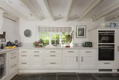 a kitchen with white cabinets and a window at The Watermill in Bodmin