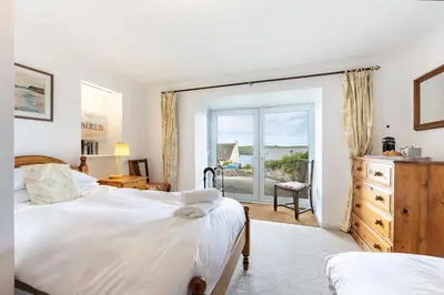 a bedroom with two beds and a sliding glass door at Stradav in Polzeath