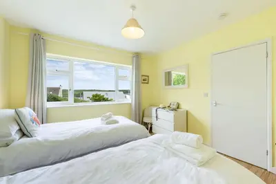 two beds in a room with a window at Stradav in Polzeath