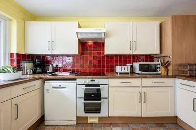 a kitchen with white cabinets and white appliances at Stradav in Polzeath