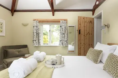 a bedroom with a large white bed and a window at Bowjy Cottage in St. Agnes
