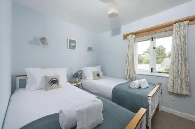 a bedroom with two beds and a window at Bowjy Cottage in St. Agnes