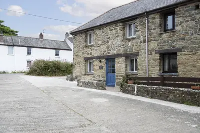 a stone house with a blue door on a street at Bowjy Cottage in St. Agnes