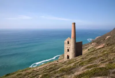 an old building on a hill next to the ocean at Bowjy Cottage in St. Agnes