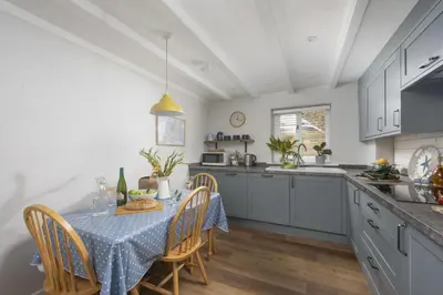 a kitchen with a table with a blue tablecloth on it at Bowjy Cottage in St. Agnes