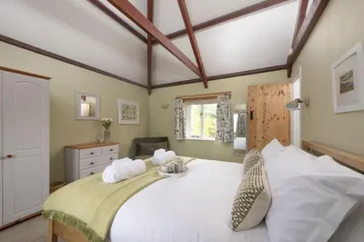 a bedroom with a large white bed with two pillows at Bowjy Cottage in St. Agnes