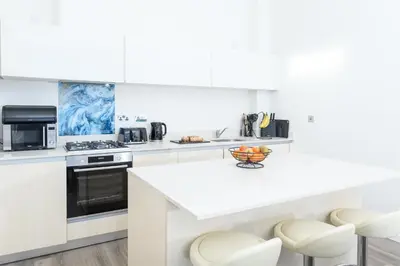 a white kitchen with white appliances and white counters at The Penthouse, 48 Zinc in Newquay