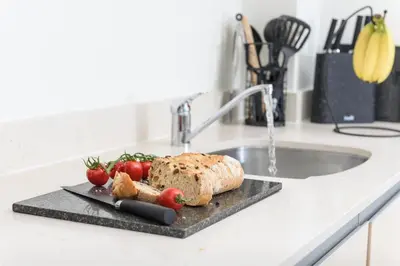 a cutting board with a loaf of bread and tomatoes on a kitchen counter at The Penthouse, 48 Zinc in Newquay