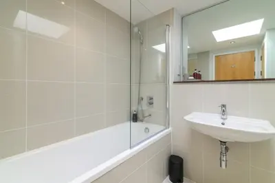 a bathroom with a sink and a shower and a mirror at The Penthouse, 48 Zinc in Newquay