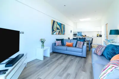a living room with a blue couch and a tv at The Penthouse, 48 Zinc in Newquay
