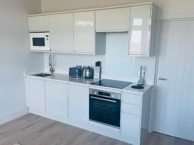 a kitchen with white cabinets and a stove top oven at Henrys in St Ives