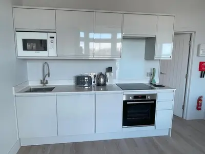 a white kitchen with a sink and a stove at Henrys in St Ives