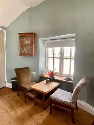 a living room with a table and chairs and a window at The Old Wood Store in Helston