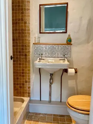 a bathroom with a sink and a toilet and a mirror at The Old Wood Store in Helston