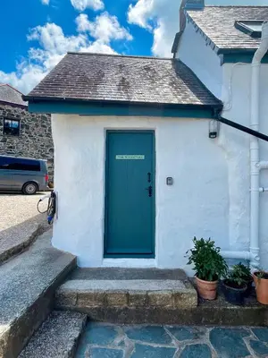 a green door on a white building with stairs at The Old Wood Store in Helston