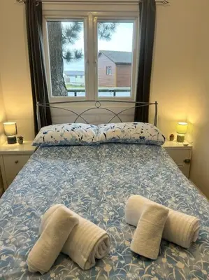 a bed with two towels on it with a window at Spacious cabin, near Padstow and 7 Bays in St Merryn