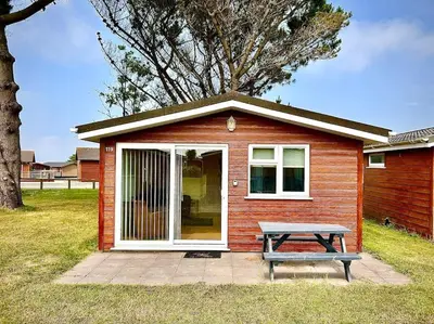 a small house with a picnic table in front of it at Spacious cabin, near Padstow and 7 Bays in St Merryn