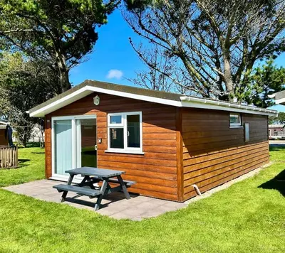 a small cabin with a picnic table in front of it at Spacious cabin, near Padstow and 7 Bays in St Merryn