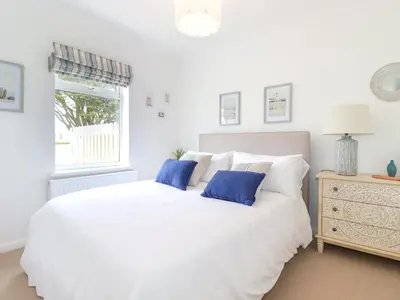 a white bed with blue pillows in a bedroom at Polwen in Padstow