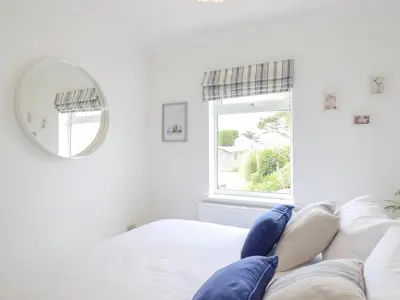 a white bedroom with a large mirror and a bed at Polwen in Padstow