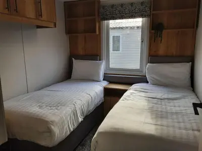 two beds in a small room with a window at Holiday Home with a Hot tub in St Austell