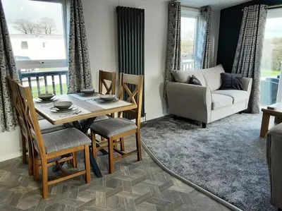 a living room with a table and chairs and a couch at Holiday Home with a Hot tub in St Austell